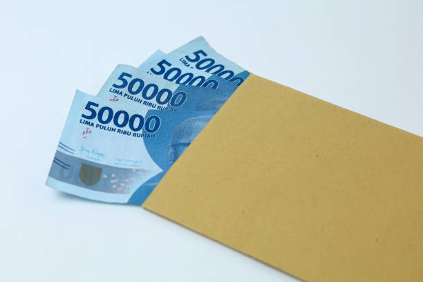 Uang dalam amplop coklat terisolasi pada latar belakang putih / iStockphoto