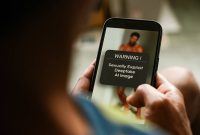 Pria mendapat pesan peringatan di ponsel tentang melihat citra seksual yang dihasilkan AI di media sosial / istockphoto